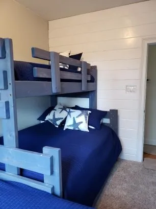 View of Bunk room with full bed on bottom and twin on top, plus a  pull-out twin trundle under the bunk.  The room also has another stand alone twin bed by the window. 