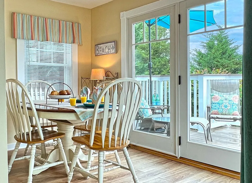 Sunny dining area opening to large private deck with garden views.
