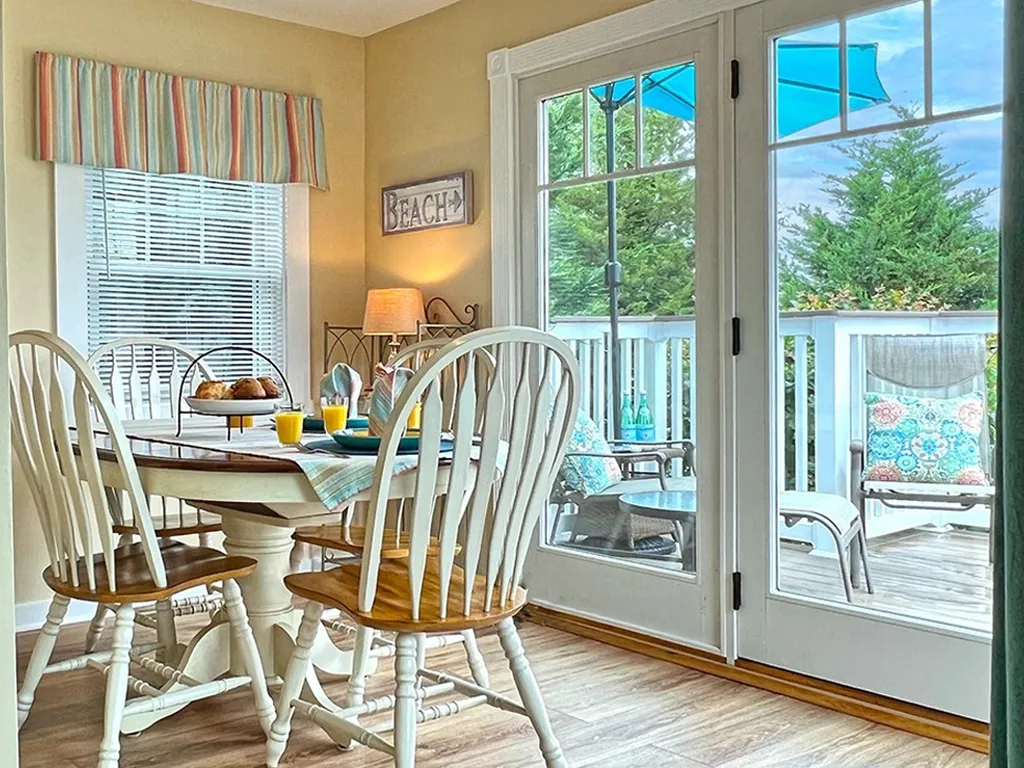Sunny dining area opening to large private deck with garden views.