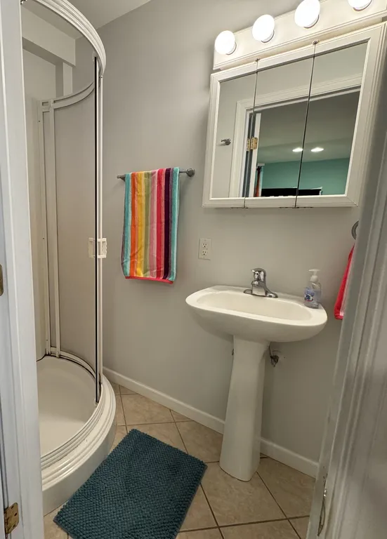 1st floor private full bathroom with pedestal sink, chair-height toilet, and walk-in shower.