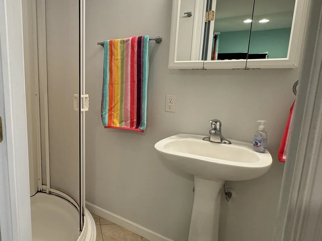 1st floor private full bathroom with pedestal sink, chair-height toilet, and walk-in shower.