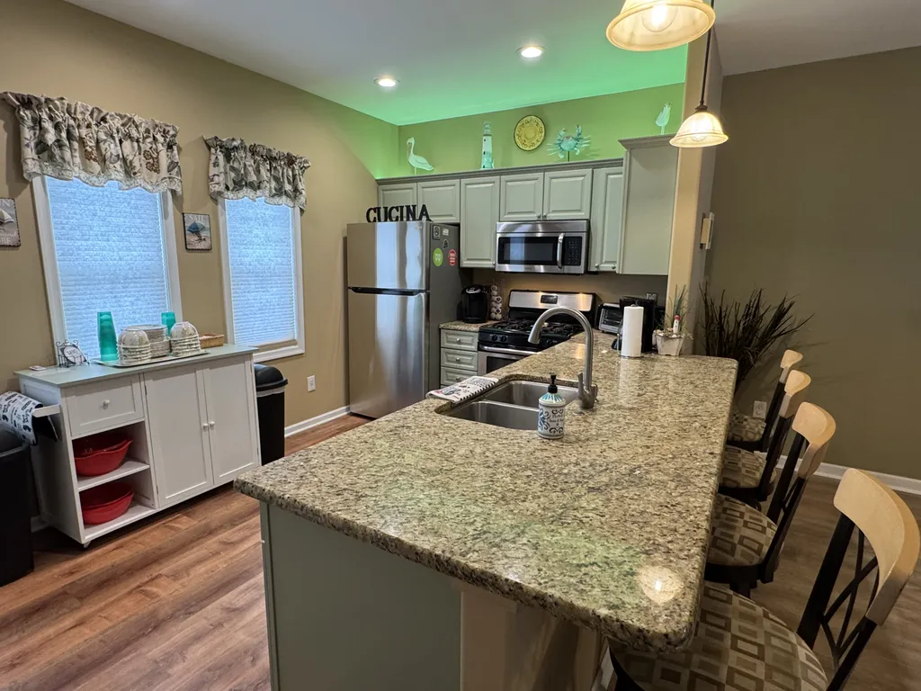 Kitchen with granite breakfast bar, 4 swivel chairs, recessed lighting, pendants