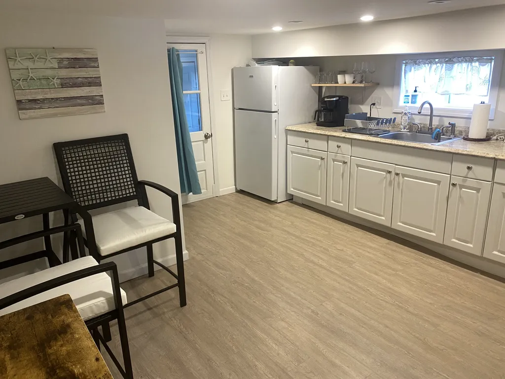 The kitchen features a fridge, coffee maker, and oven