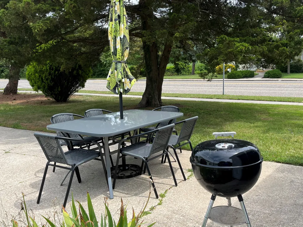Outdoor table, six chairs and a charcoal grill with umbrella - enjoy dining outside if you wish