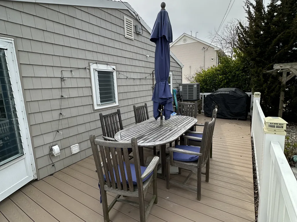 deck has a grill, table and chairs, umbrella, outdoor rinse station and games