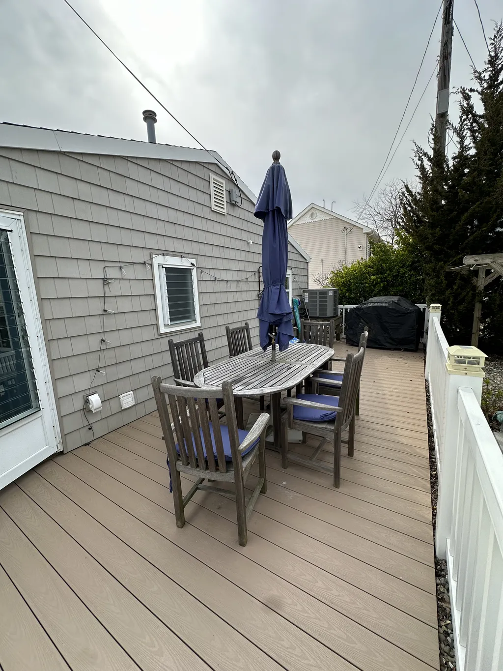 deck has a grill, table and chairs, umbrella, outdoor rinse station and games