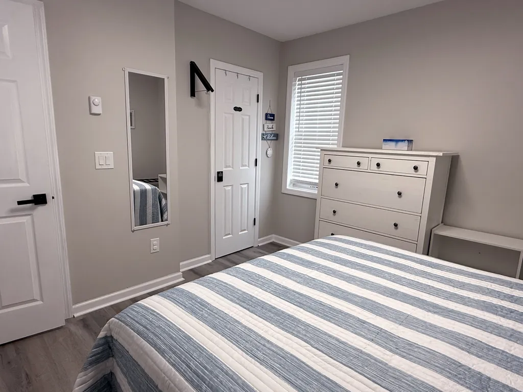 Bedroom features dresser, mirror and clothes hanger.