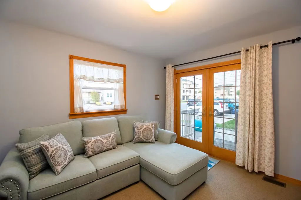 The beach family room is a sunlit haven, adorned with coastal decor and featuring French doors that open up to a private deck, offering a seamless indoor-outdoor connection.