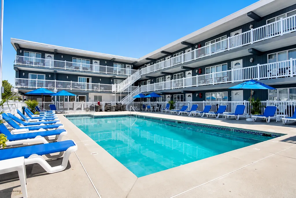 Large heated pool with plenty of loungers, grills, and shaded overhang with tables