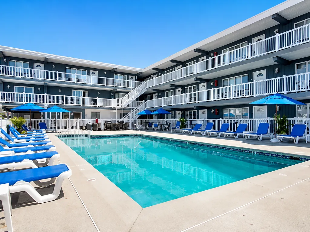 Large heated pool with plenty of loungers, grills, and shaded overhang with tables